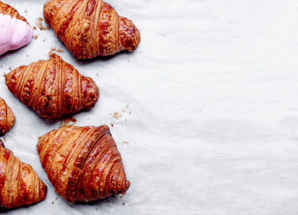 istock Croissants.  Fresh baked croissants on white baking paper  with copy space for text. Flat lay. 1005918478