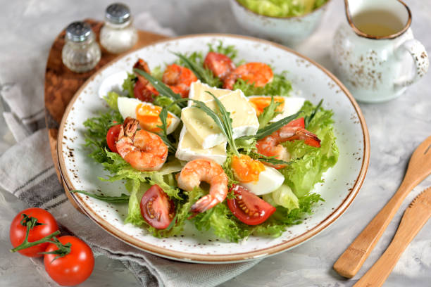 istock Healthy lettuce salad with arugula, large shrimps, cherry tomatoes, boiled egg, brie cheese and grated parmesan cheese. 1005918756