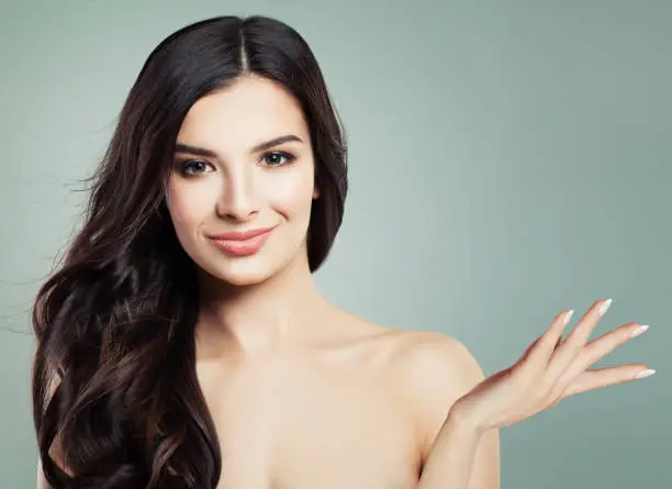 Young Smiling Woman with HealthySkin and Long Wavy Hairstyle Showing Empty Copy Space on the Open Hand, Beauty Portrait. Product Placement and Advertising Marketing Concept