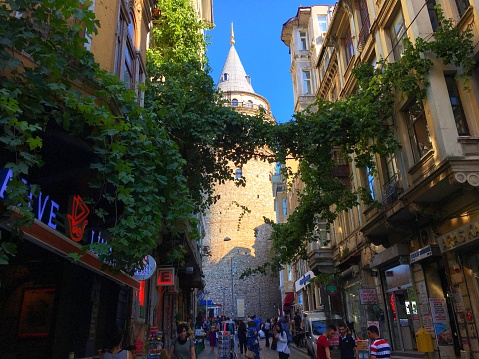 Galata, Istanbul, Turkey - July 16, 2018: Galata Tower from a narrow street and people crowd.