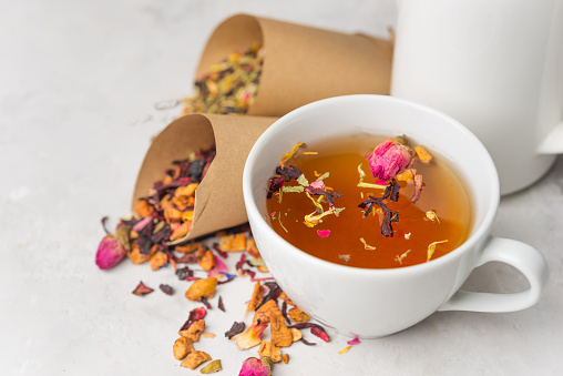 Fresh tea from medicinal herbs, dry fruits with rose petals in a white Cup. Summer refreshing drink.