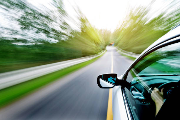 istock Man hand driving a car through a forest 1005935040