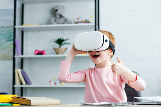 istock adorable happy schoolchild using virtual reality headset and showing thumb up 1005935144