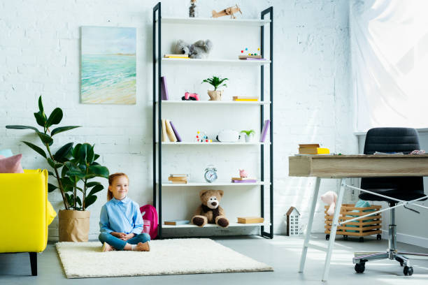 istock adorable smiling child sitting on carpet at home 1005935214