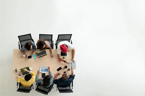 Top view of diverse people of creative team group using smartphone, mobile phone, tablet and computer laptop. Overhead view of asian young creative start up meeting. Have copy space for fill text.