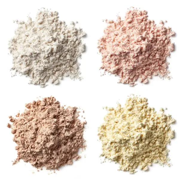 Photo of Four various heaps of protein powder (vanilla, strawberry, chocolate, banana)