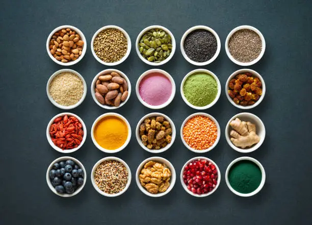 Photo of Various colorful superfoods in bowls on dark background