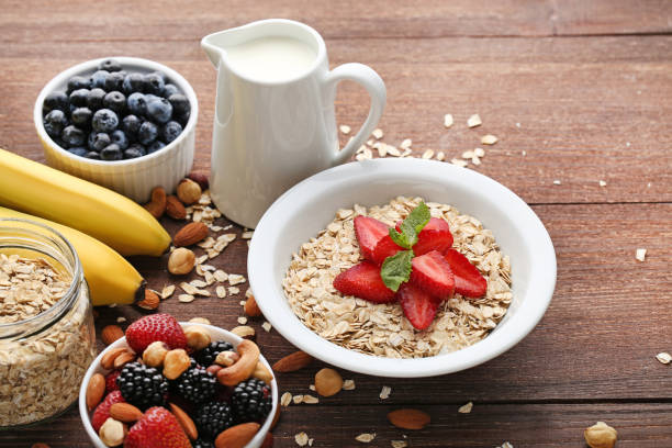 istock Oat flakes in plate with berries, nuts and milk on wooden table 1005966068