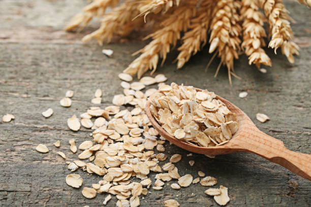istock Oat flakes in spoon with wheat ears on wooden table 1005966834