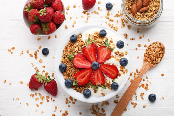 istock Tasty granola with berries in plate on wooden table 1005967018