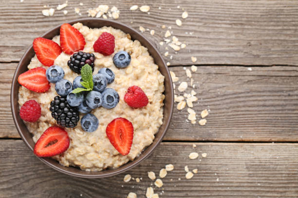 istock Oatmeal in bowl with berries on wooden table 1005975010