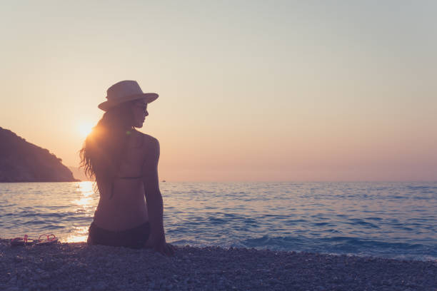 istock Beautiful young woman, enjoying sunset on the beach 1005978582