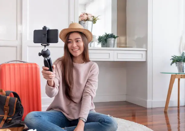 Photo of Asian young female blogger recording vlog video with mobile phone live streaming when travel.online influencer on social media viral concept.