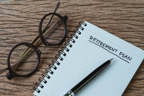 istock Blank note pad with pen and handwriting headline as Retirement Plan with eyeglasses on wood table, planning for saving and investment for expense after retire 1005984010