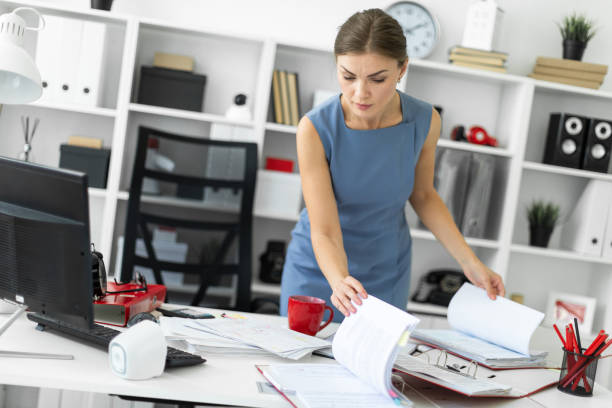 istock A young girl stands near a table in the office and scrolls through the documents. 1005988070