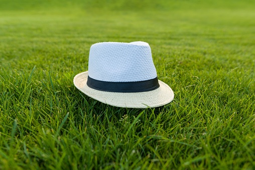 Straw hat on green grass lawn texture