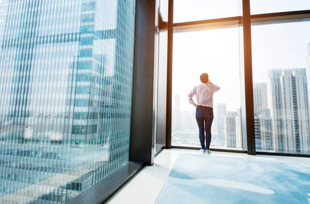 istock Woman standing by the window and using phone 1006002060