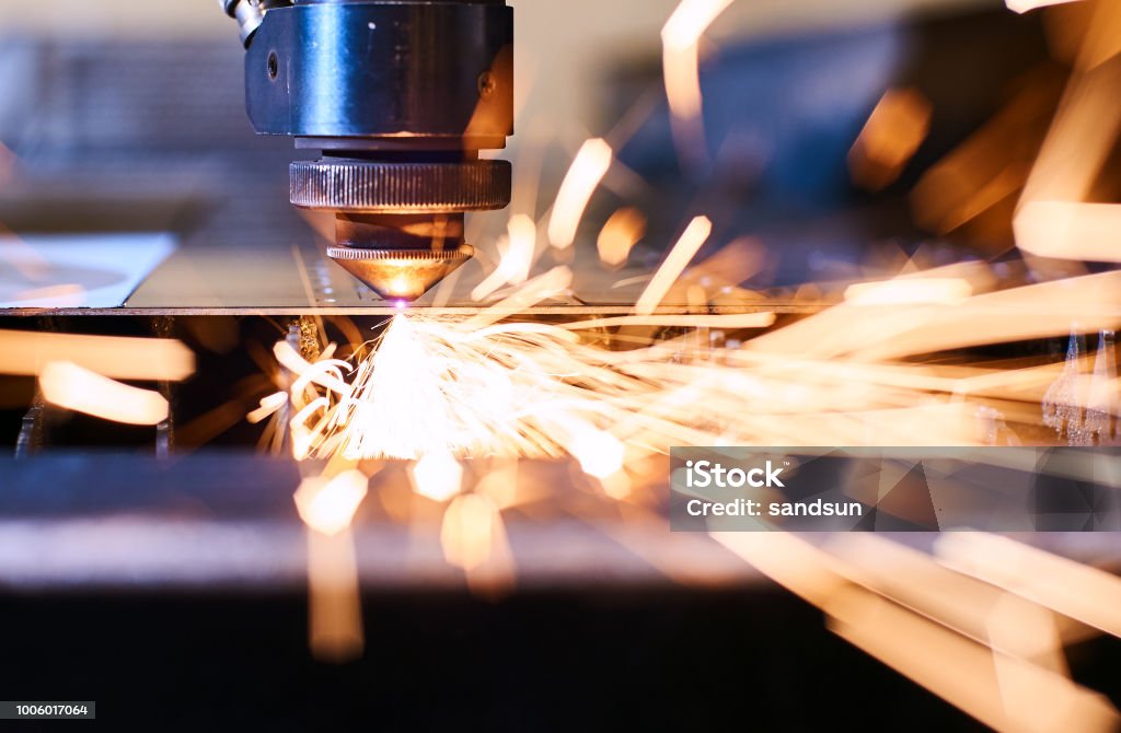 CNC Laser cutting of metal, modern industrial technology. Small depth of field. CNC Laser cutting of metal with sparks, modern industrial technology. Small depth of field. Manufacturing Stock Photo