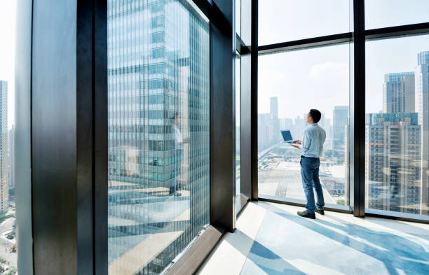istock Businessman standing by the window and using laptop 1006018358