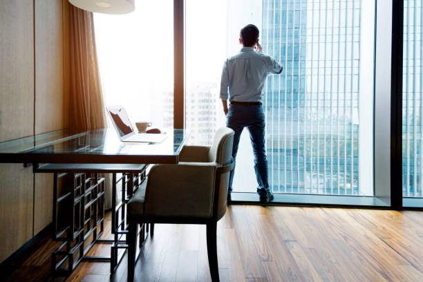 istock Businessman standing by the window using phone 1006022754