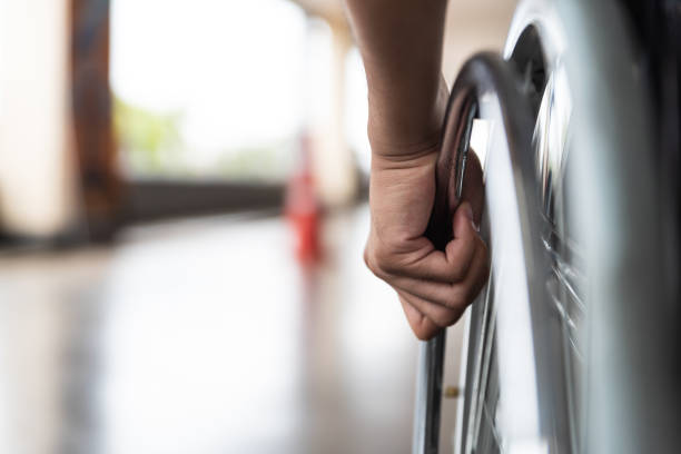 closeup mano de hombre en la rueda de la silla de ruedas de discapacitados - parálisis fotografías e imágenes de stock
