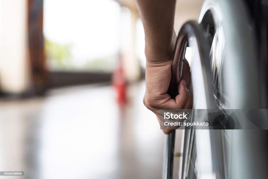 primo piano uomo disabile mano sulla ruota della sedia a rotelle - Foto stock royalty-free di Sedia a rotelle