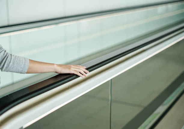 istock woman holding on handrail when ascending escalator 1006044798
