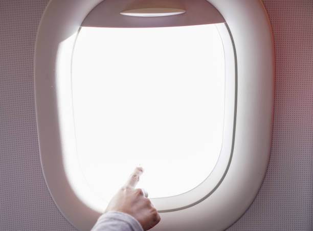istock Female Hand Pointing Out of Plane Window 1006048136