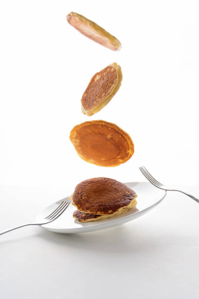 This is a close up color image of a plate of pancakes on a white table.  Blurred background is intentional.  Cropped right.