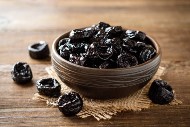 istock Prunes in ceramic bowl on rustic wooden table. Dried plums. 1006057776