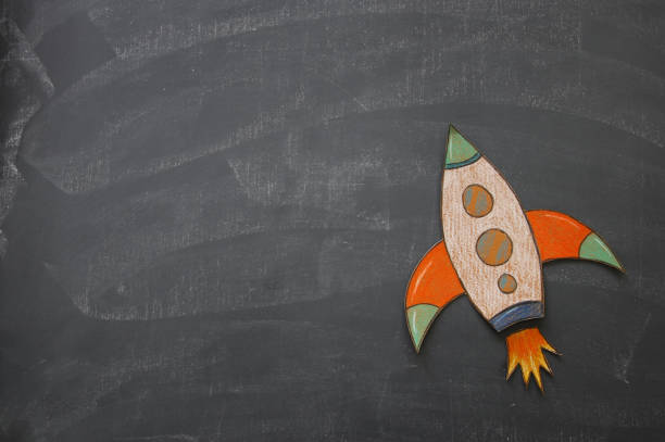 istock Rocket cut from paper and painted over class room blackboard background. 1006063106