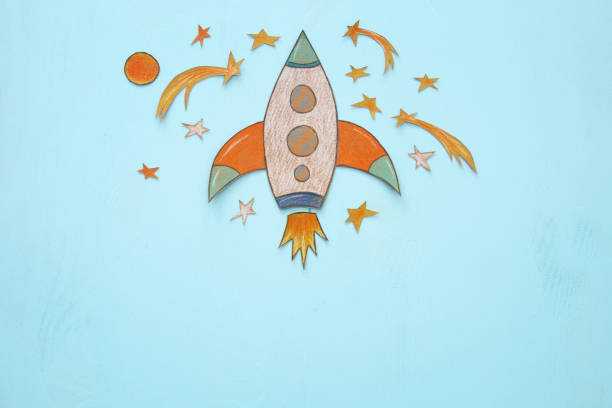 istock Rocket cut from paper and painted over wooden blue background. 1006063322