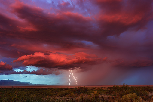 Thunderstorm with lightning bolts striking at sunset.