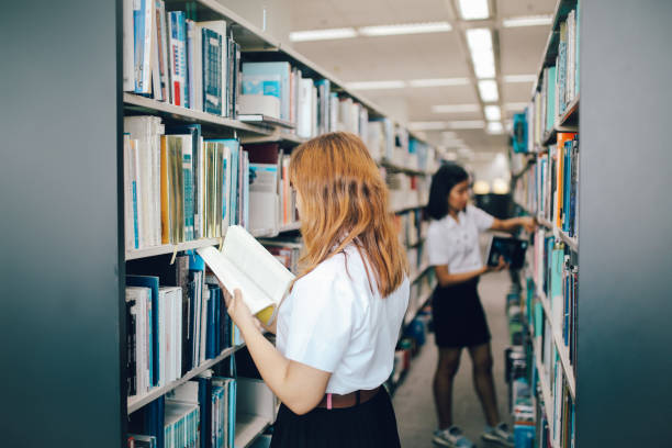 istock Two young Asian students searching for books in the library 1006071670
