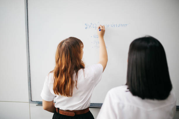 istock Asian students in uniforms doing lectures in the classroom, writing on the whiteboard 1006073890