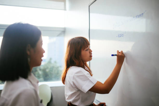 istock Asian students in uniforms doing lectures in the classroom, writing on the whiteboard 1006074966