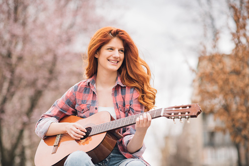 Young woman with acoustic guitar at the park