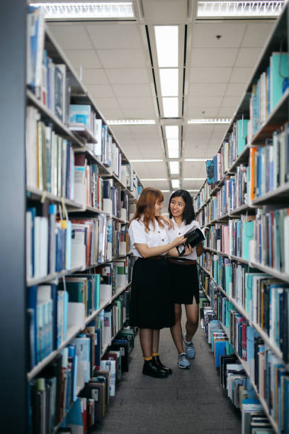istock Two young Asian students searching for books in the library 1006077484