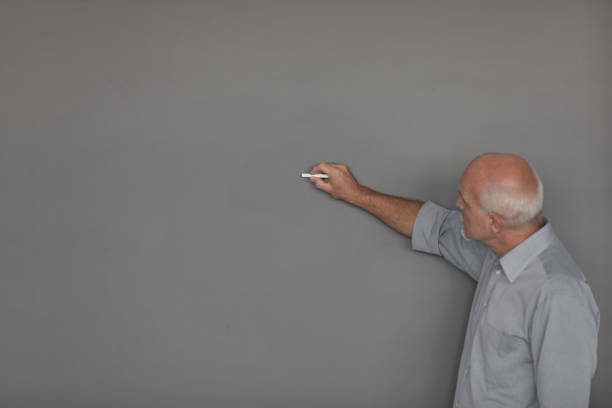 istock Male teacher writing on chalkboard 1006078512