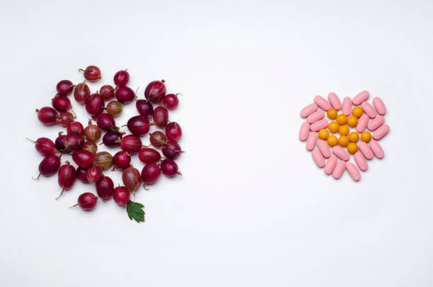 bunch of gooseberries and vitamin pills on a white background. healthy lifestyle concept - vibrant color healthcare and medicine healthy lifestyle vitamin pill imagens e fotografias de stock