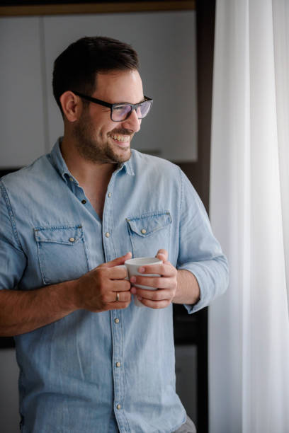 istock Happy handsome man drinking coffee in the morning looking through window 1006081196