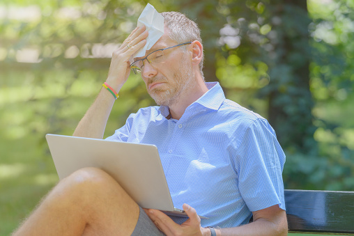 Man suffers from heat while working with laptop