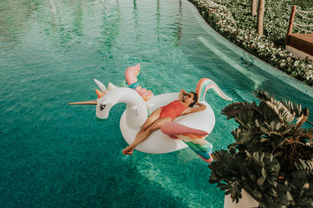 mujer despreocupada en unicornio inflable - float fotografías e imágenes de stock