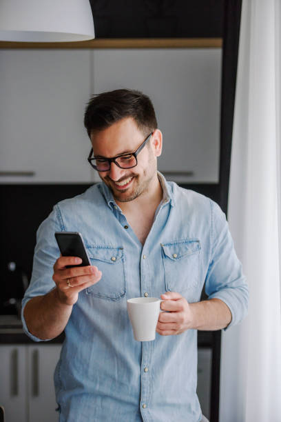 istock Happy handsome man drinking coffee in the morning looking through window 1006082274