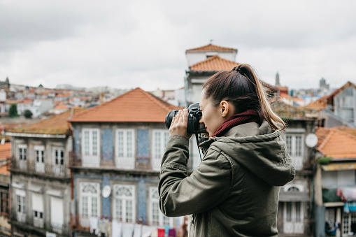 A professional travel photographer or tourist photographs a beautiful urban landscape in Porto in Portugal. Professional photography or interesting hobby.