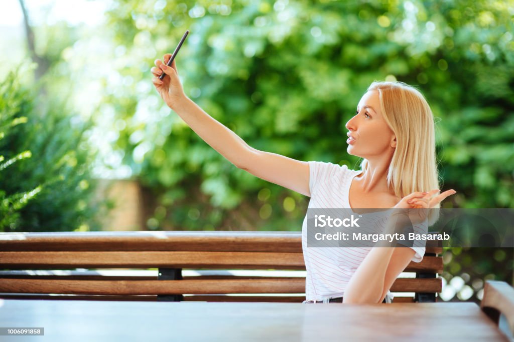 Joven sonriente haciendo foto selfie en smartphone - Foto de stock de A la moda libre de derechos