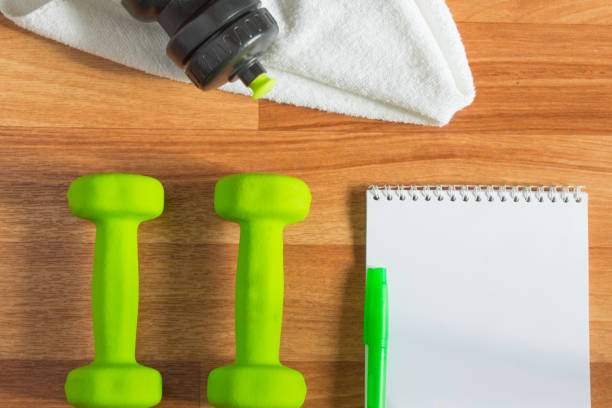 istock Plan workouts with dumbbells, towel, Water Bottle, Notepad on wooden background 1006092068