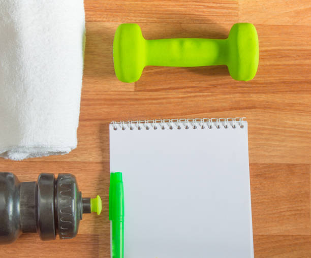 istock Plan workouts with dumbbells, towel, Water Bottle, Notepad on wooden background 1006092110