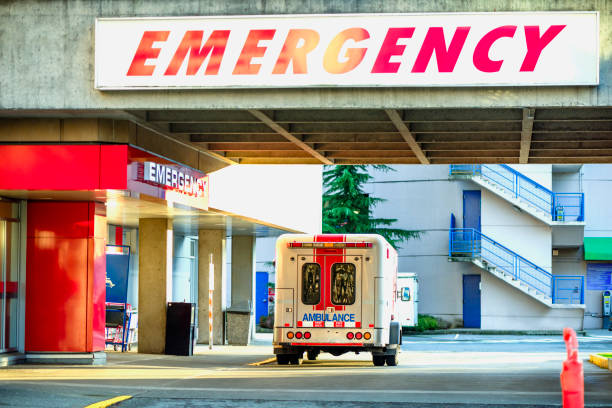 moderna auto ambulanza parcheggiata vicino all'ingresso di emergenza dell'ospedale durante il giorno - disastri foto e immagini stock