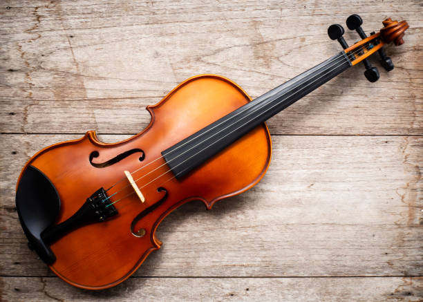 istock Brown violin on wooden background. Top view with dark vignette. 1006114020